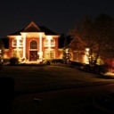 House at night with dramatic exterior lighting and nice landscaping.